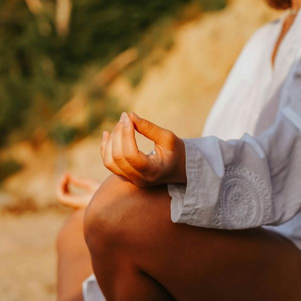 Person meditating peacefully outdoors during a sunset.