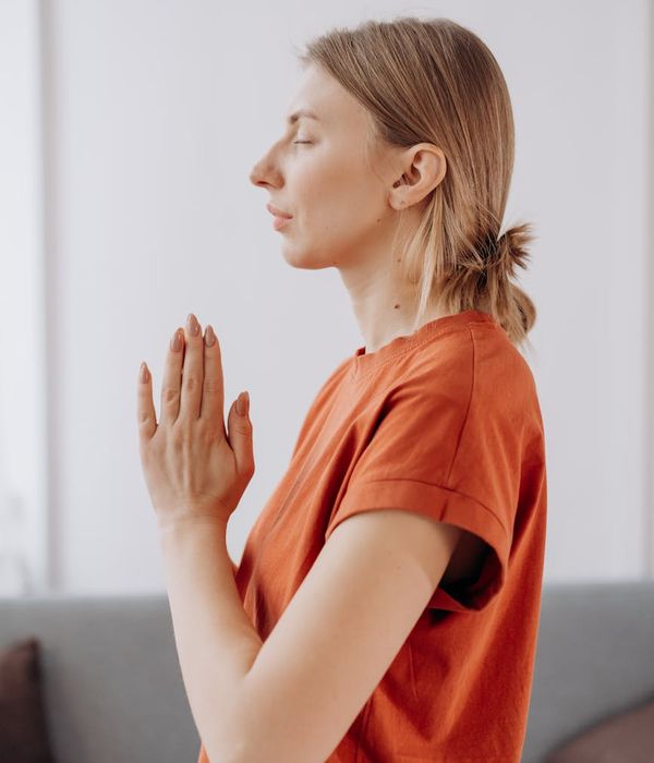 Woman in a calm yoga pose in a dark room with a subtle red glow.